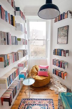 a living room filled with lots of books on the shelves and a bean bag chair