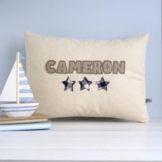 a pillow with the word cameron embroidered on it next to a sailboat and other items