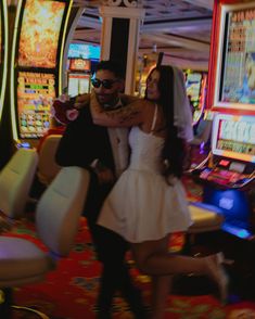 a man and woman standing next to each other in front of slot machines