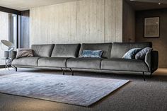 a grey couch sitting on top of a rug in a living room next to a window