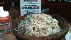 a wooden bowl filled with coleslaw next to a sign that reads made with passion