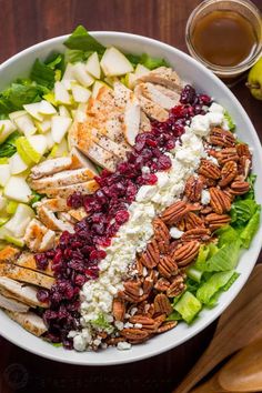 a salad with chicken, apples, cranberry sauce and pecans on the side