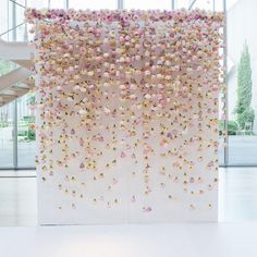 a white wall with pink and yellow flowers hanging from it's sides in an open space