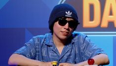 a man wearing sunglasses and a beanie sitting at a table