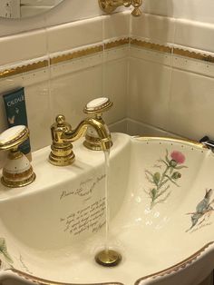 a white sink with gold faucet and flowers on it