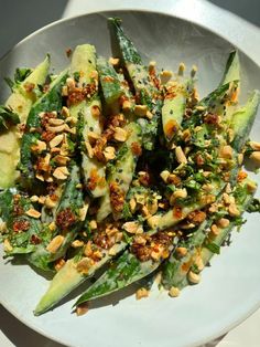 a white plate topped with green vegetables covered in nuts and seasoning on top of it