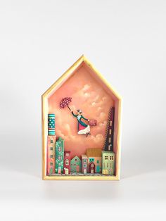 a small doll house with a girl holding an umbrella in the air and buildings on both sides