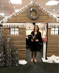 a woman is standing in front of a house made out of wood and fake snow