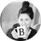 a black and white photo of a woman holding a coffee mug with the letter b on it