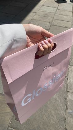 a person holding a pink shopping bag with the word glosier on it's side