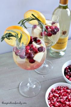 two wine glasses filled with fruit and garnished with rosemary