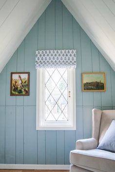 a chair and window in a room with blue painted wood paneling on the walls