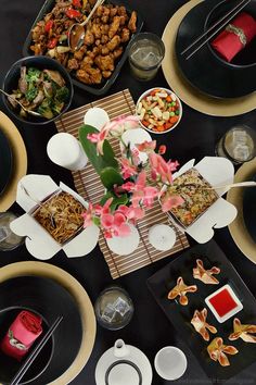 a table topped with black plates and bowls filled with different types of food next to utensils