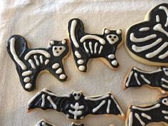 decorated cookies with black and white icing are arranged in the shape of cats and bats