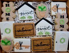 decorated cookies in a box with the words welcome home and some house shaped decorations on them