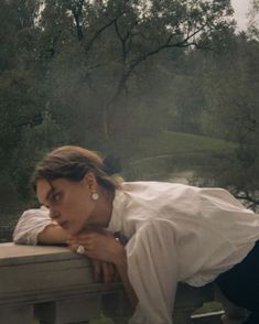 a woman leaning on a fence with her head resting on the hand of another person's arm