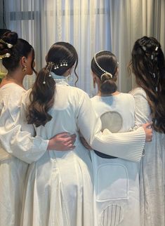 three bridesmaids in white dresses are looking at their reflection in the bathroom mirror