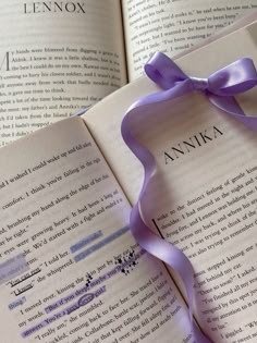 an open book with a purple ribbon on top of it and the words annika