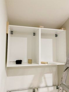 a ladder is in front of two white shelves