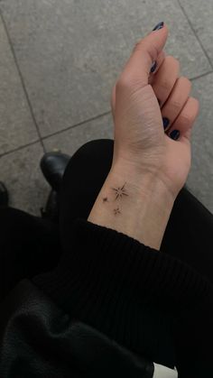 a woman's hand with a small star tattoo on her left wrist and the other arm