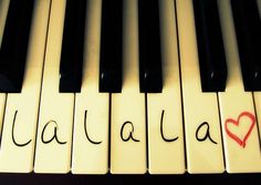 an image of piano keys with words written on them in spanish and english, along with a red heart