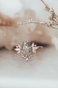 a diamond ring sitting on top of a table next to a twig with leaves