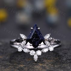 a black diamond ring with three pear shaped diamonds on the side and two pear shaped diamonds on the other side