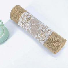 a roll of burlock with white lace on it next to a small vase