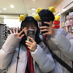 two people with pikachu ears taking a selfie in front of a store