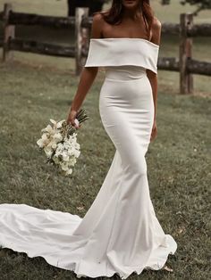 a woman in a white dress holding a bouquet and posing for the camera with her hand on her hip