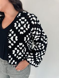 This beautifully crafted cardigan features a classic black crochet base adorned with an elegant white pattern that adds a touch of contrast and sophistication. Designed to be worn open, it’s perfect for layering over any tank top or blouse, instantly transforming your outfit with its intricate, artisanal design. Available in sizes small, medium, and large Color: Black with White crochet pattern Lydia is 5'5" and has a 34d bust. She is wearing a medium. Cropped length Black trim 100% Acrylic Pair Black Crochet Top For Spring Layering, Black Crochet Top For Layering In Fall, Fitted Fall Cardigan With Crochet Trim, Fitted Cardigan With Crochet Trim For Fall, Fitted Crochet Trim Cardigan For Fall, Black Textured Knit Crochet Top, Black Textured Knit Crochet Top For Spring, Crochet Trim Cardigan For Layering, White Crochet Pattern