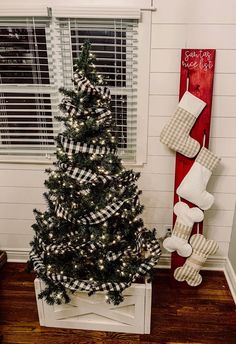 a decorated christmas tree in a living room next to a window with white and black decorations