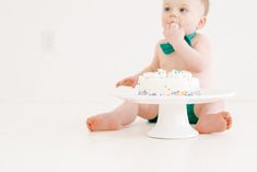 a baby sitting on the floor with a cake in front of him and eating it