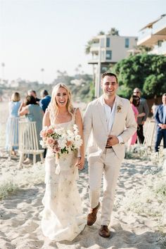 a bride and groom walking down the beach after their wedding ceremony in santa clement, california