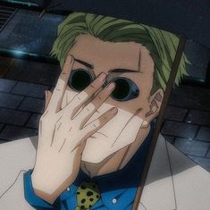 a man with green hair holding his hands to his face and covering his eyes in front of him