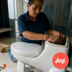 a man sitting on top of a white toilet in a bathroom next to other items