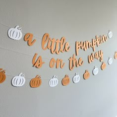 a little pumpkin is on the way banner with cutout pumpkins hanging from it