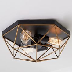 a black and gold light fixture with two lights on it's sides, in an octagonal shape