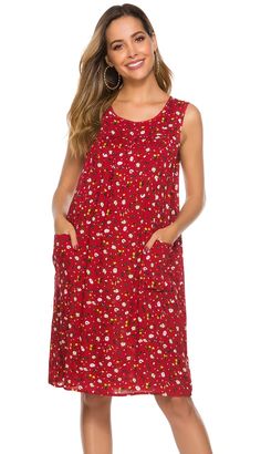 a woman is wearing a red dress with white flowers on it and she has her hands in her pockets