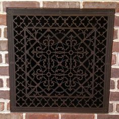 a decorative iron grille on the side of a brick wall