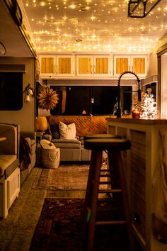 a living room filled with lots of furniture and christmas lights hanging from the ceiling above