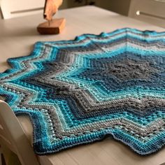 a crocheted blanket sitting on top of a table next to a wooden spoon