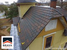 an aerial view of a yellow house with brown shingles on the roof and windows