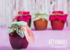 three jars filled with jam sitting next to each other on a purple cloth covered table