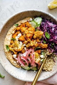 a bowl filled with rice, meat and veggies next to a lemon wedge