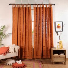 a living room with orange curtains and a white couch