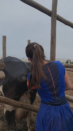 a woman in a blue dress is petting a cow