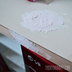 an unfinished counter top with white paint on it and a pink vase in the background