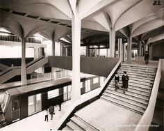 an old photo of people walking up and down the stairs in a building with arches