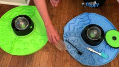 two bowls with spoons and toothbrushes sitting on the floor next to each other